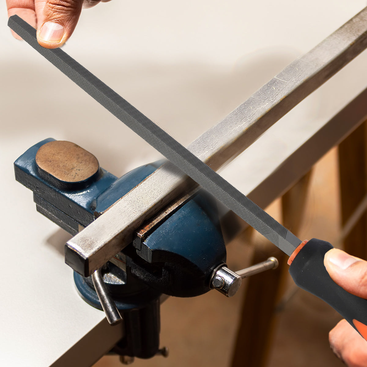 Person using a file to sharpen a metal rod held in a vise.