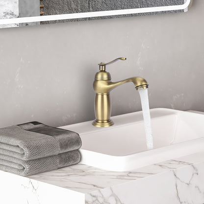 Gold faucet on a sink with running water, gray towels, and a mirror in the background.