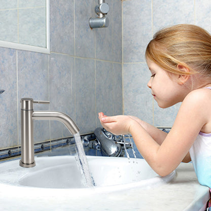 Child washing hands under a running faucet in a bathroom.