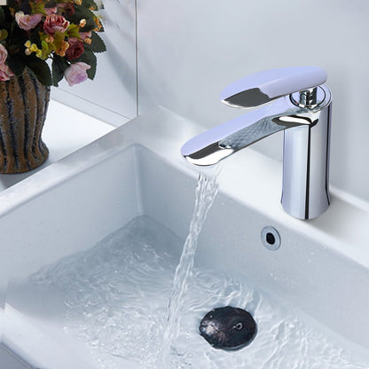 Chrome faucet with water flowing into a sink, with flowers in the background.