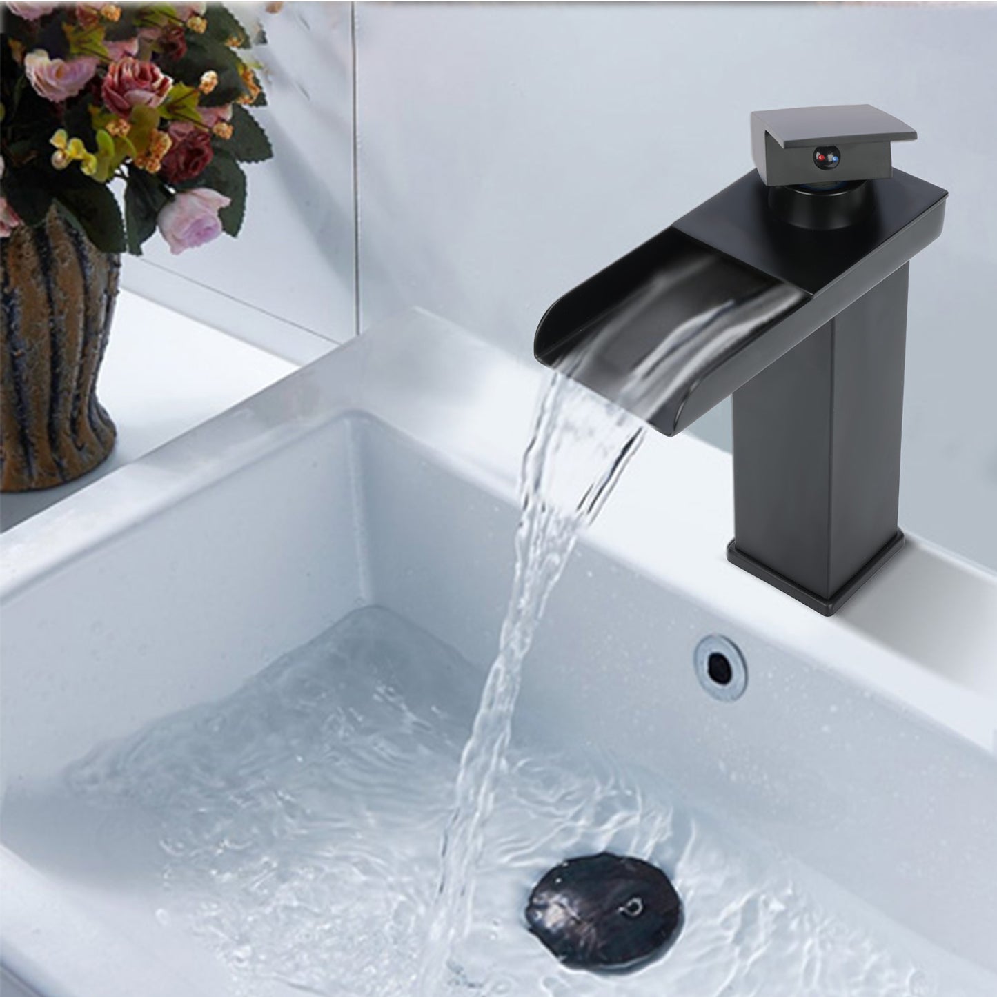 Black faucet with water flowing into a sink, with flowers in the background.