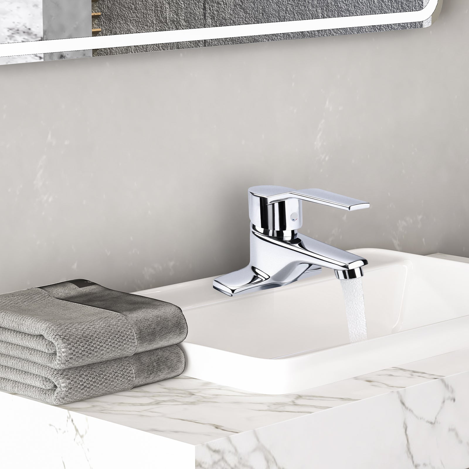 Chrome faucet on a marble sink with gray towels and a mirror in the background