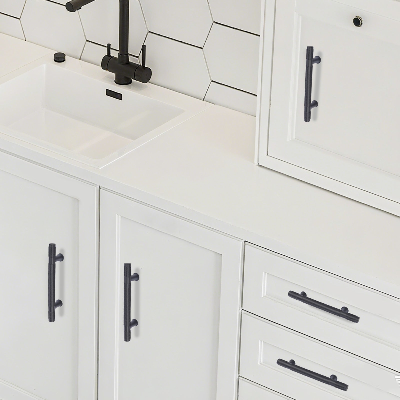 White kitchen cabinets with black handles and a tiled backsplash.