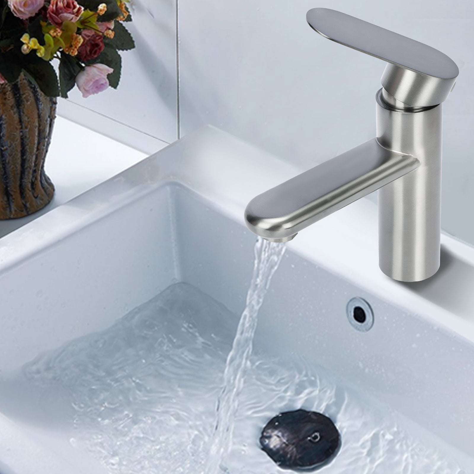 Stainless steel faucet in a sink with water flowing, decorative flowers in the background.
