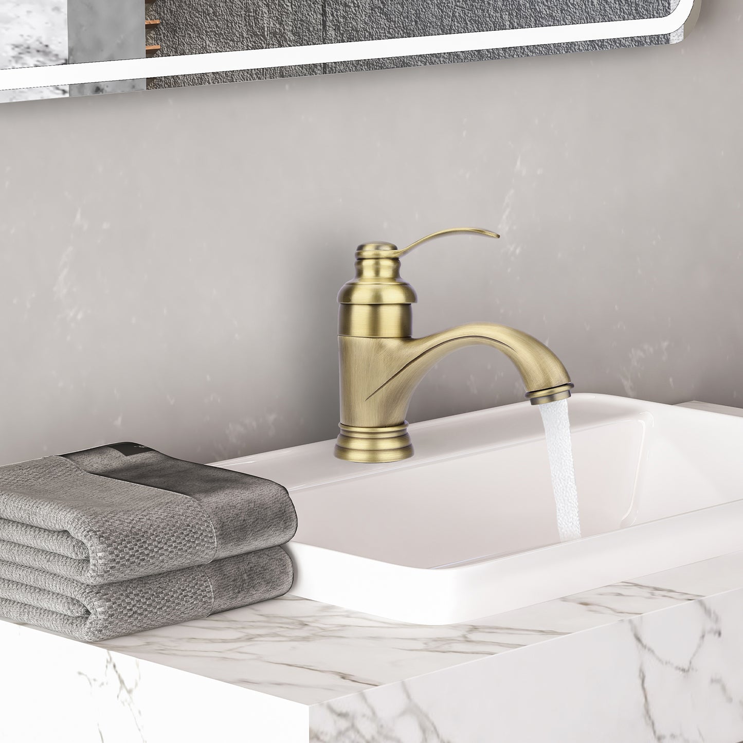 Gold faucet on a sink with gray towels and a marble countertop