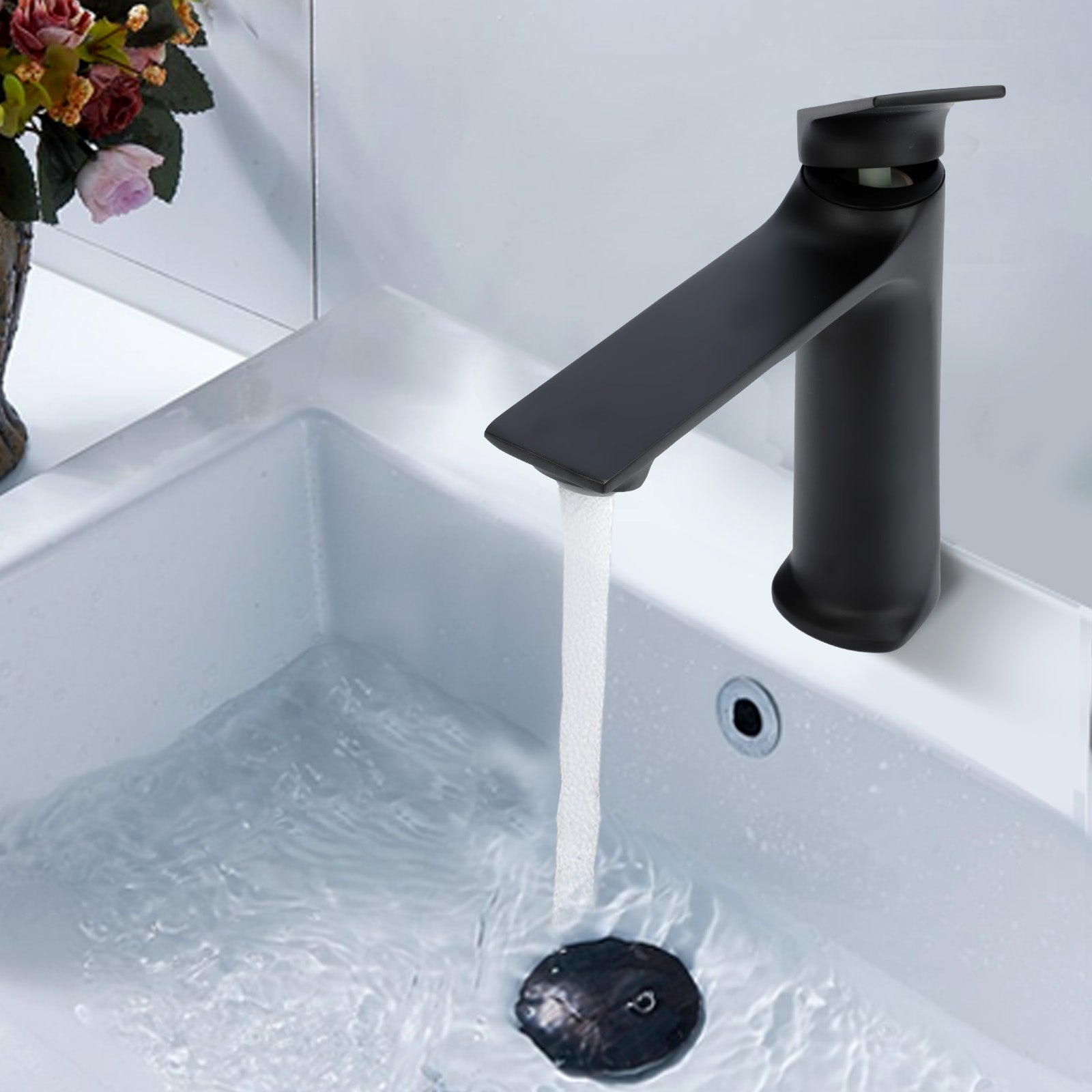 Black faucet with water flowing into a sink on a light gray background