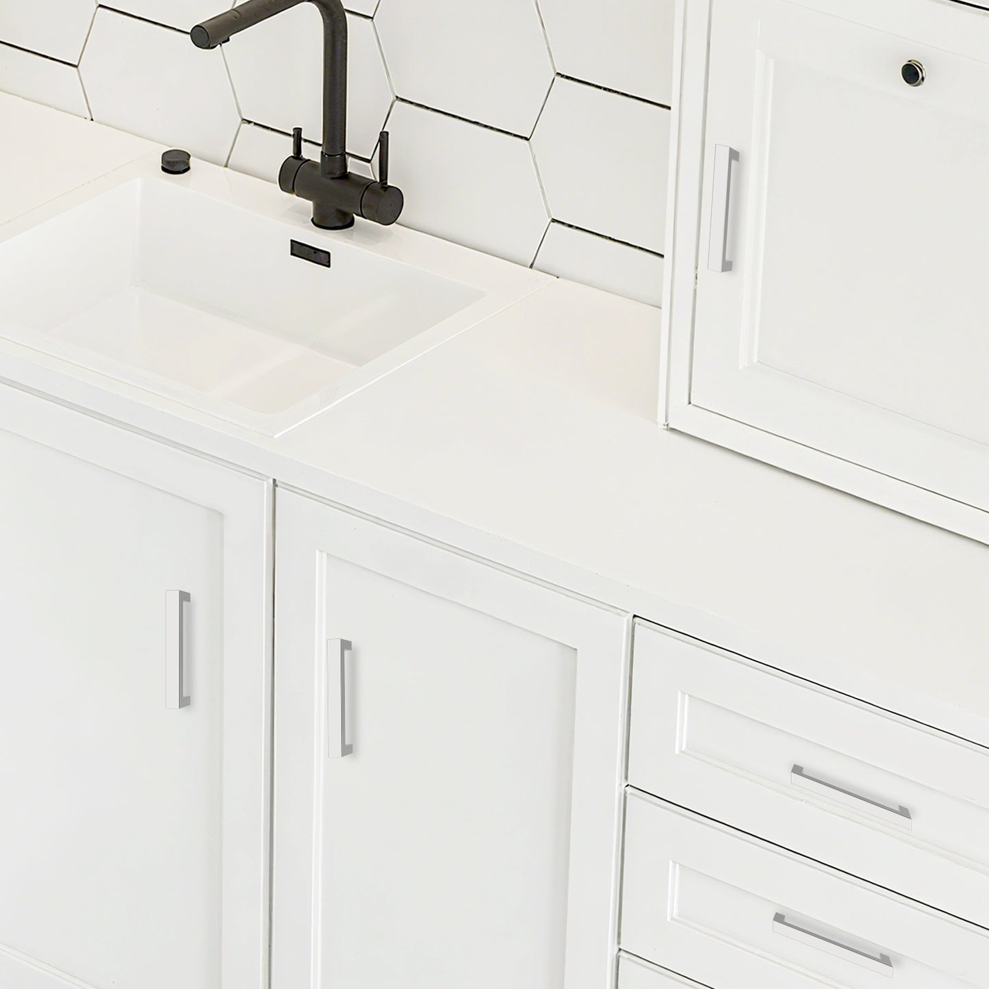 White kitchen cabinets with a black faucet and tiled backsplash.