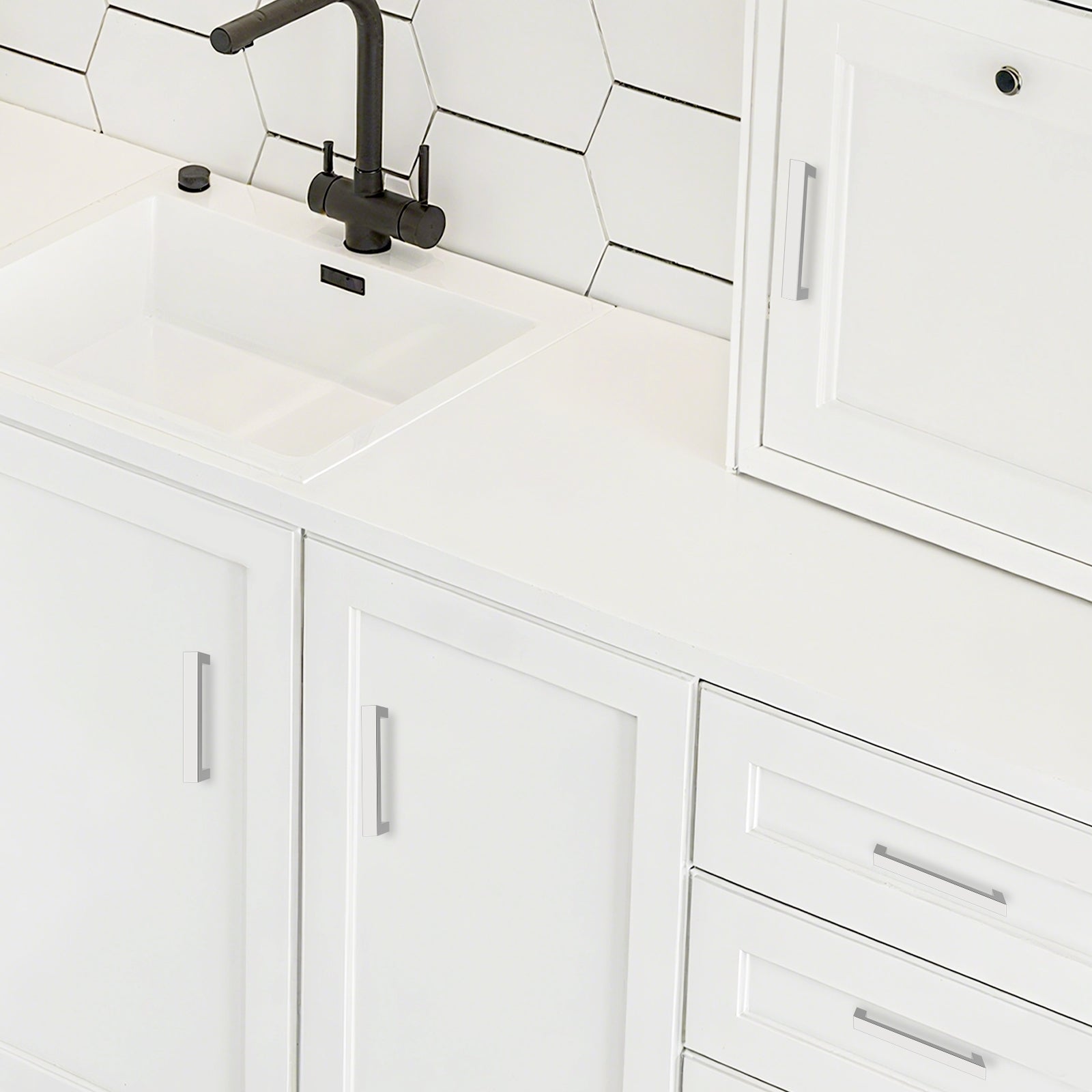 White kitchen cabinets with a black faucet and tiled backsplash.