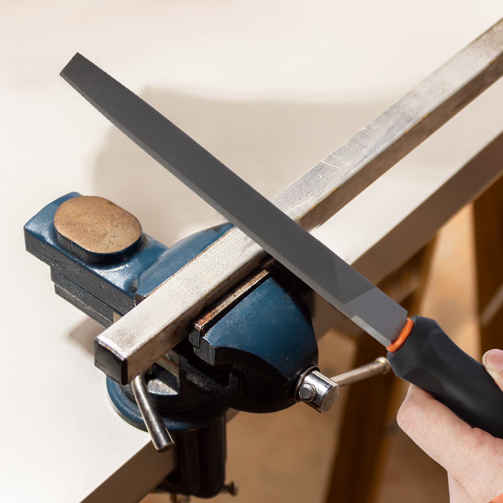 Person sharpening a knife on a whetstone held in a blue vise.
