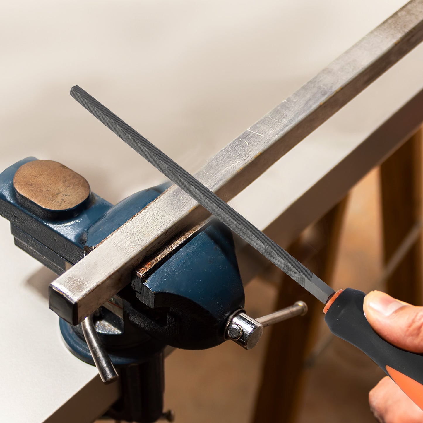 Person sharpening a blade on a metal rod using a sharpener attached to a bench vice.