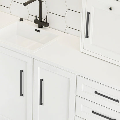 White kitchen cabinets with black handles and a tiled backsplash.