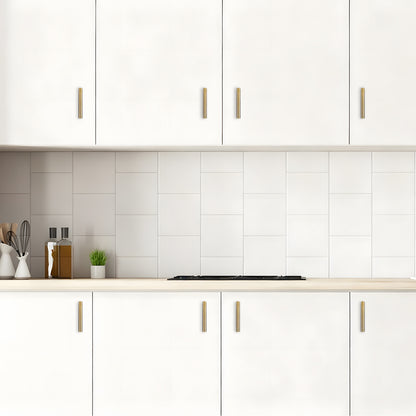 Modern kitchen with white cabinets, gold handles, and a tiled backsplash.