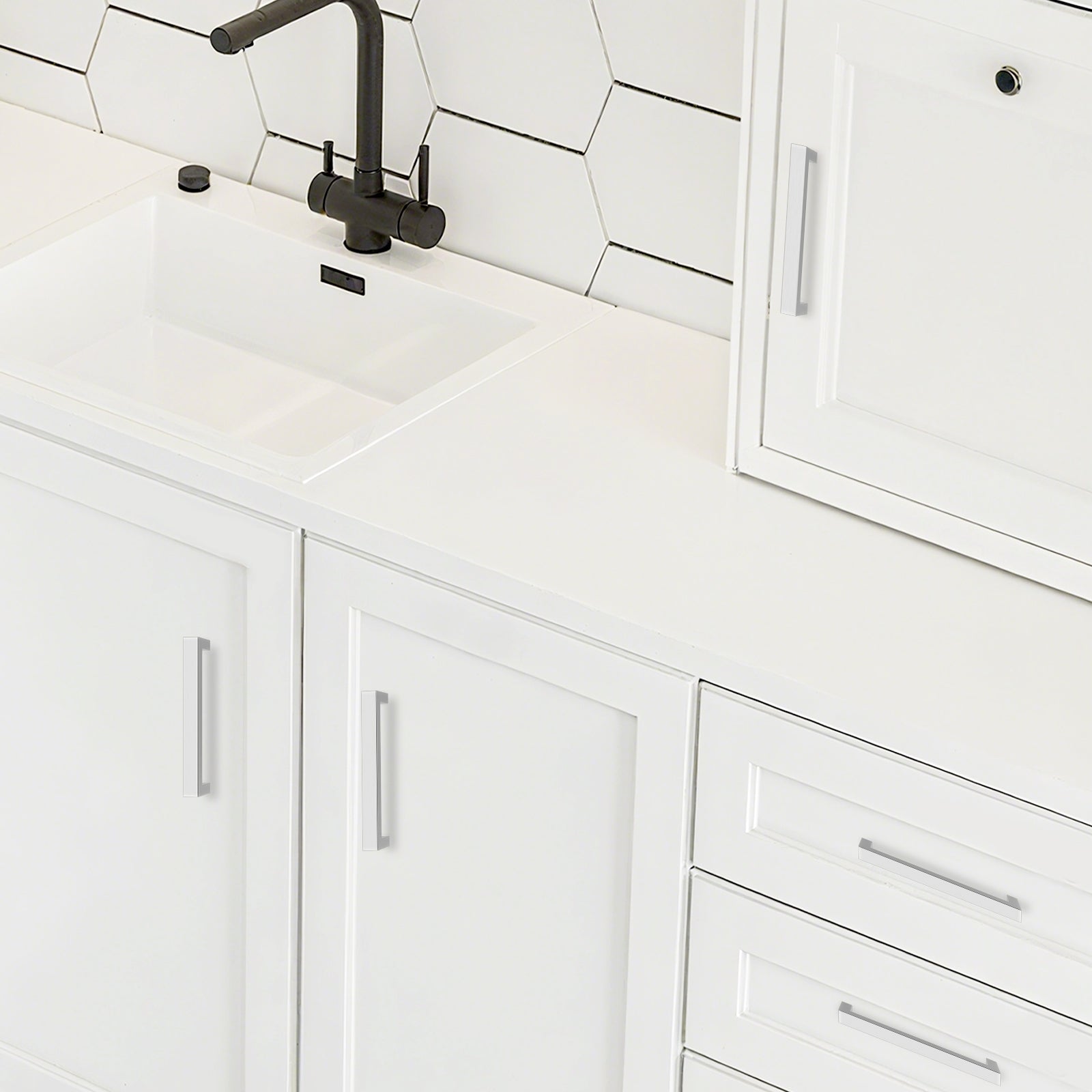 White kitchen cabinets with a black faucet and tiled backsplash.