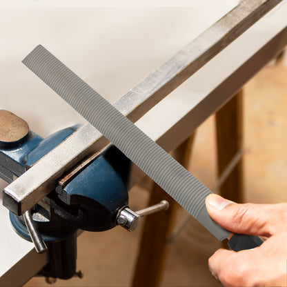 Person sharpening a blade with a whetstone on a wooden surface