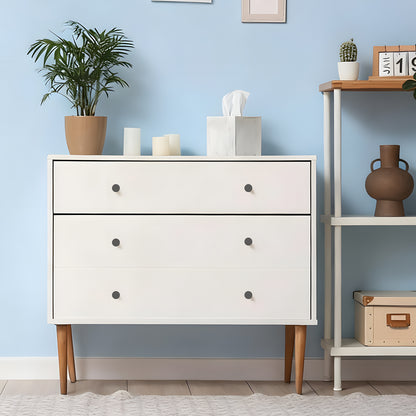 White dresser with wooden legs against a light blue wall with decorative items.