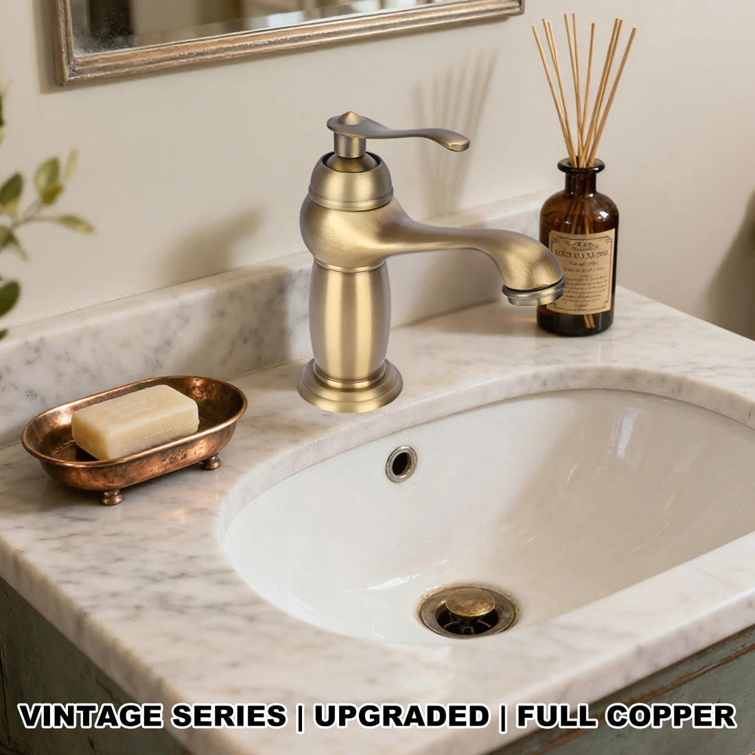 Bathroom sink with gold faucet, soap dish, and reed diffuser on marble countertop.