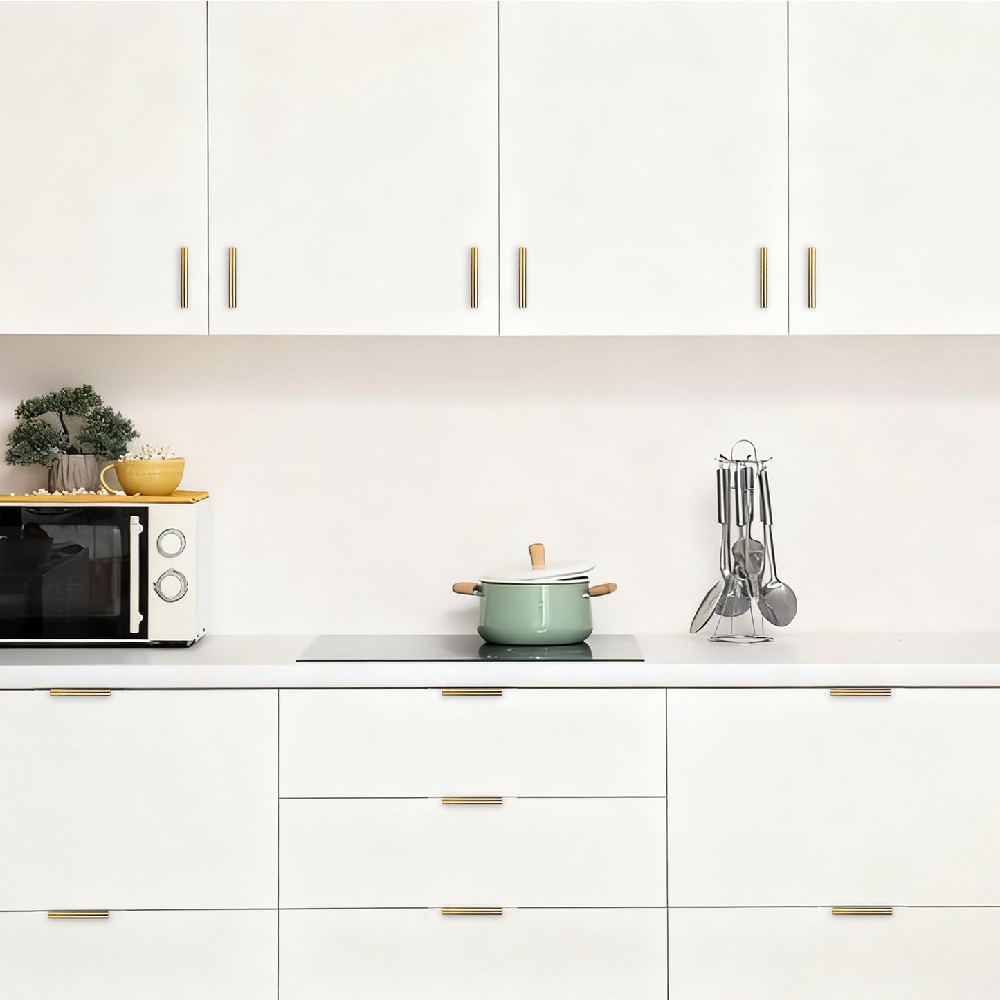 Modern kitchen with white cabinets, a green pot, and various utensils.
