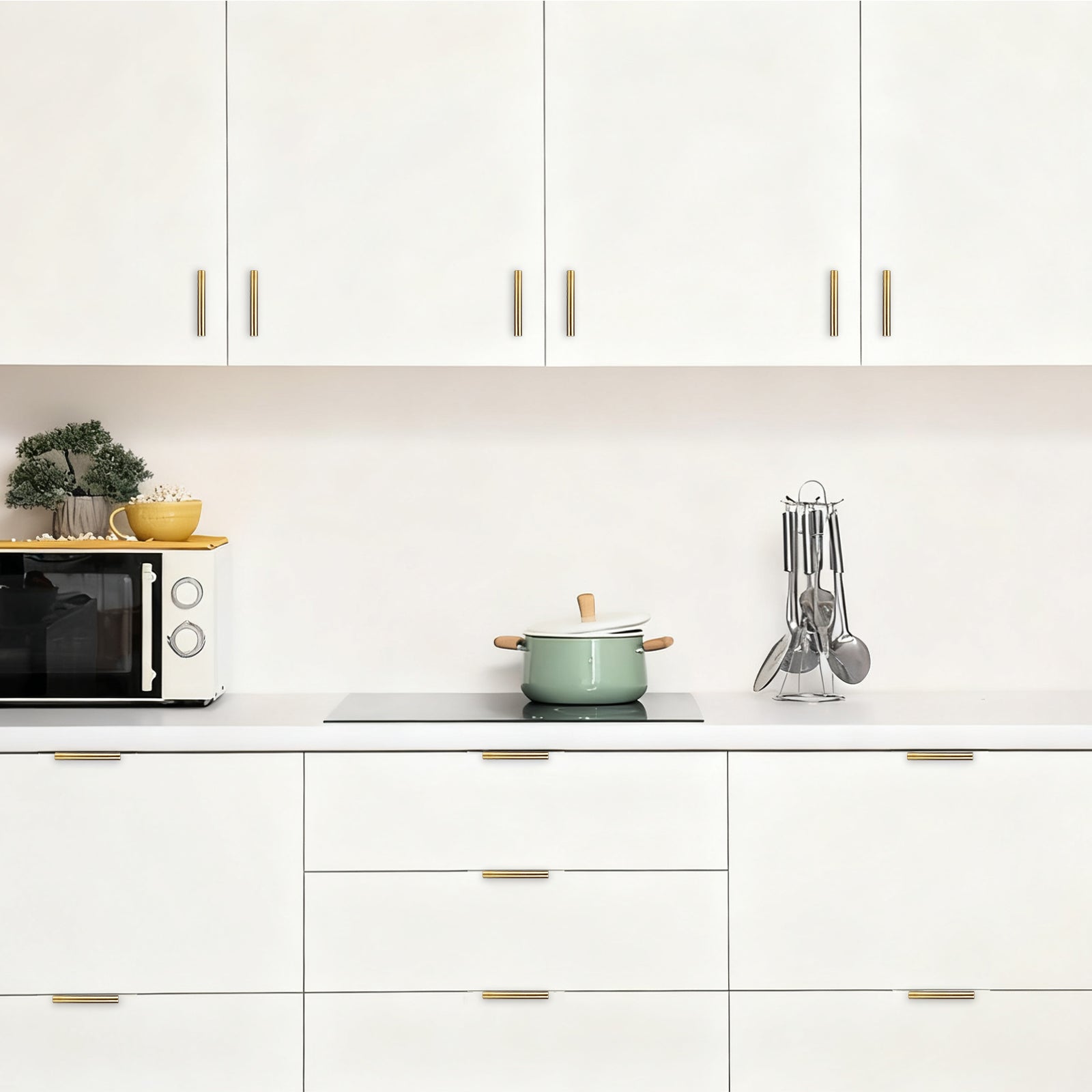 Modern kitchen with white cabinets, a green pot, and various utensils.