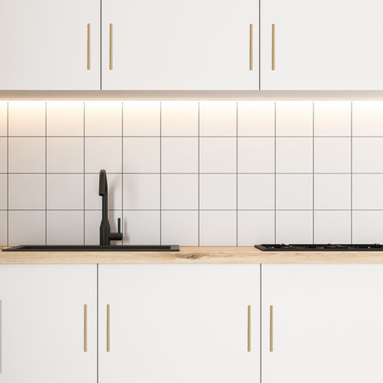 Modern kitchen with white tiled backsplash, wooden countertop, and gold cabinet handles.