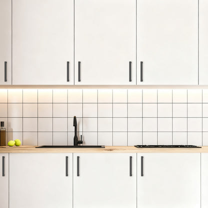 Modern kitchen with white cabinets, black handles, and a tiled backsplash.