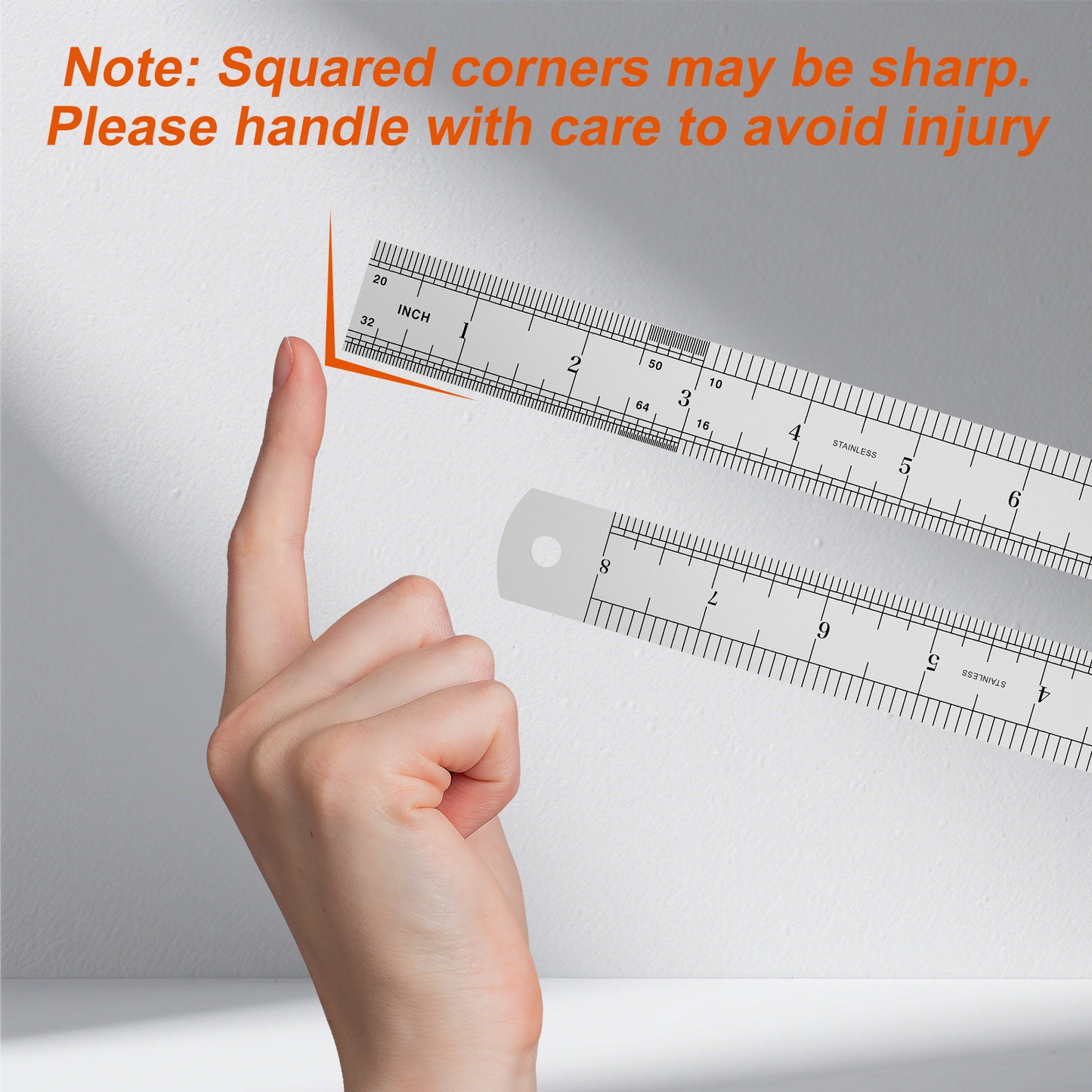 Hand holding a ruler with a warning about squared corners being sharp on a gray background